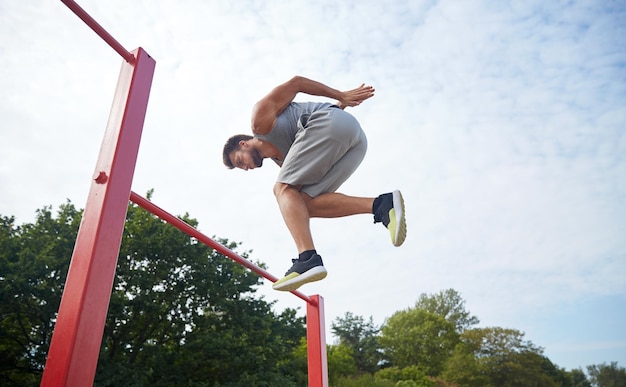 concetto di fitness, sport, esercizio fisico, formazione e stile di vita - giovane che salta sulla barra orizzontale all'aperto