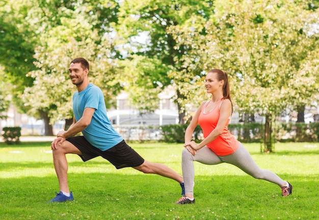 concetto di fitness, sport, formazione e stile di vita - coppia sorridente che si estende all'aperto