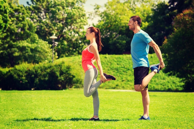 concetto di fitness, sport, formazione e stile di vita - coppia sorridente che si estende all'aperto