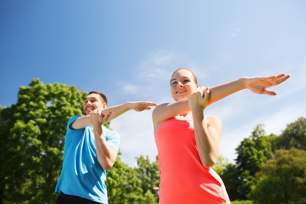 concetto di fitness, sport, formazione e stile di vita - coppia sorridente che si estende all'aperto