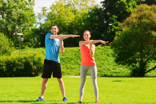 concetto di fitness, sport, formazione e stile di vita - coppia sorridente che si estende all'aperto