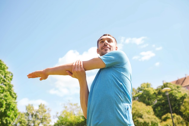 concetto di fitness, sport, formazione e stile di vita - uomo sorridente che allunga la mano all'aperto