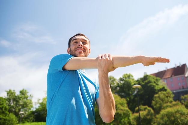 concetto di fitness, sport, formazione e stile di vita - uomo sorridente che allunga la mano all'aperto