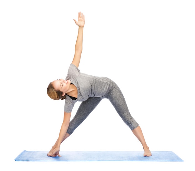 concetto di fitness, sport, persone e stile di vita sano - donna che fa la posa del triangolo yoga sul tappeto