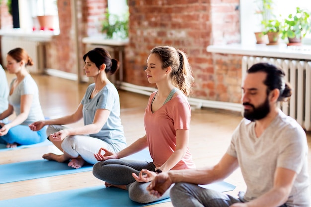 concetto di fitness, yoga e stile di vita sano - gruppo di persone che meditano nella posa del loto in studio