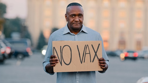 Concetto di fobia della vaccinazione delle persone L'uomo afroamericano anziano adulto si trova nella strada della città con un cartello con il testo No VAX per protestare contro il vaccino non esaminato contro il covid 19 fermare l'immunizzazione