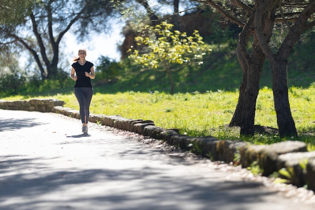 Concetto di forma fisica una donna adulta che fa jogging nel parco verde