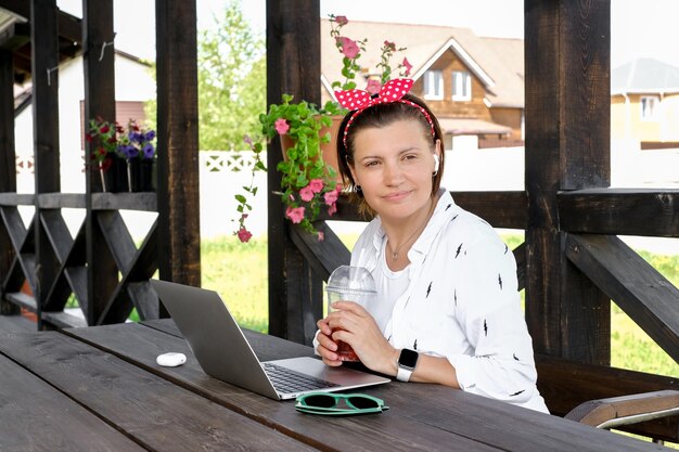 Concetto di freelance Bella donna che usa il computer portatile nella terrazza del caffè all'aperto Lavora e viaggia nella calda estate