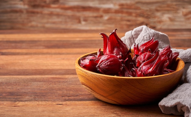 concetto di frutti rossi freschi fatti in casa roselle o ibisco sabdariffa in una ciotola di legno sullo sfondo