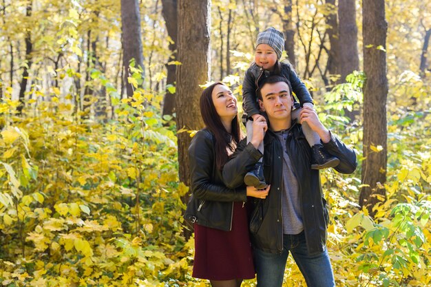 Concetto di genitorialità, caduta e persone - giovane famiglia felice nel parco autunnale.