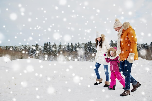 concetto di genitorialità, moda, stagione e persone - famiglia felice con bambino in abiti invernali che cammina all'aperto