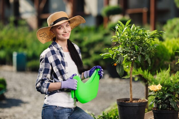 Concetto di giardinaggio. Ritratto di belle piante d'innaffiatura del giardiniere femminile nel giardino nel giorno di estate caldo.