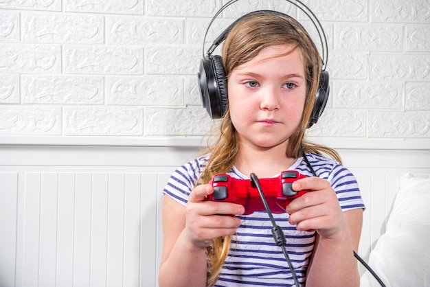 Concetto di giocatori per bambini Preteen caucasica bambina che tiene il joystick per giocare ai videogiochi a casa con gli auricolari