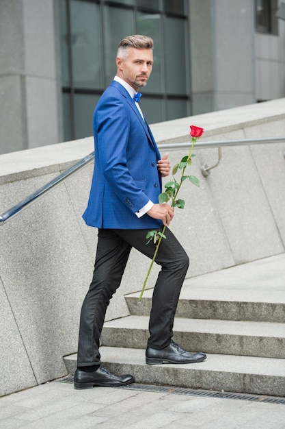 Concetto di giorno di san valentino uomo smoking elegante con regalo di fiori di rosa di san valentino per il giorno di san valentino