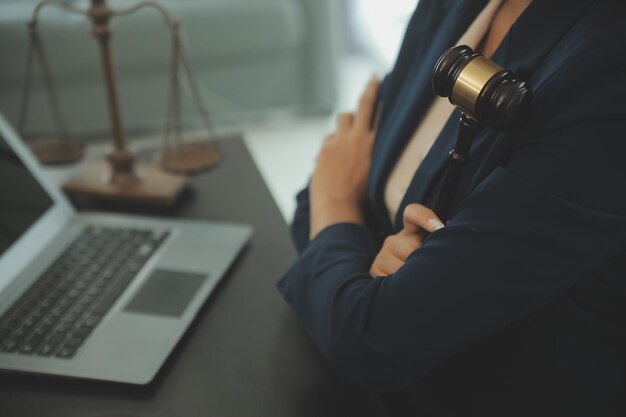 Concetto di giustizia e diritto Giudice maschile in un'aula di tribunale con il martelletto che lavora con il computer e gli occhiali della tastiera di aggancio sul tavolo alla luce del mattino