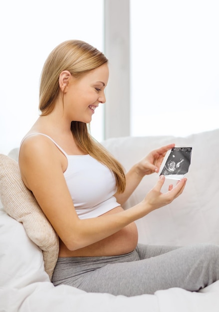 concetto di gravidanza, maternità e felicità - donna incinta felice seduta sul divano con immagine ad ultrasuoni