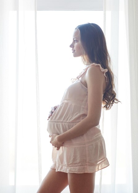 concetto di gravidanza, maternità, persone e aspettativa - donna incinta felice in chemise vicino alla finestra a casa