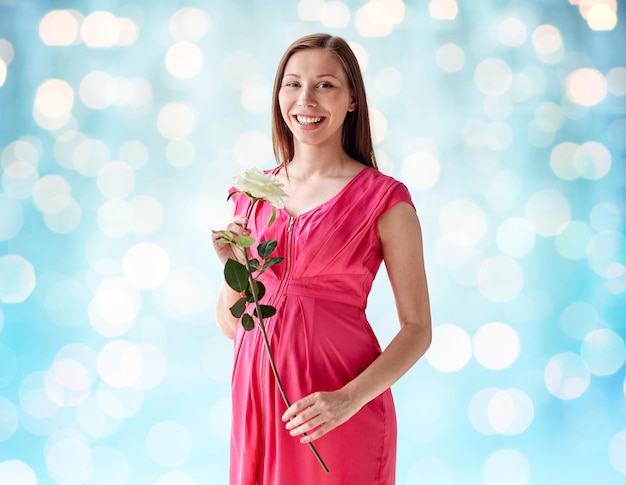 concetto di gravidanza, maternità, persone, vacanze e aspettativa - felice donna incinta con fiore rosa bianco su sfondo blu luci vacanze