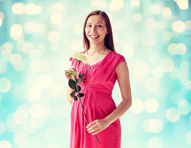 concetto di gravidanza, maternità, persone, vacanze e aspettativa - felice donna incinta con fiore rosa bianco su sfondo blu luci vacanze