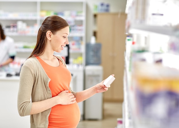 concetto di gravidanza, medicina, farmaceutica, assistenza sanitaria e persone - donna incinta felice con farmaci in farmacia