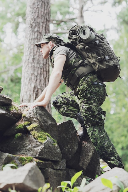 concetto di guerra, escursionismo, esercito e persone - giovane soldato o ranger con zaino che cammina nella foresta