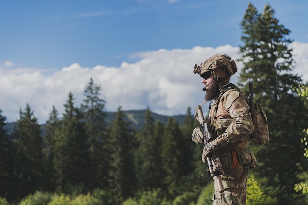Concetto di guerra un soldato barbuto in un'uniforme delle forze speciali che combatte un nemico in un'area forestale selecti