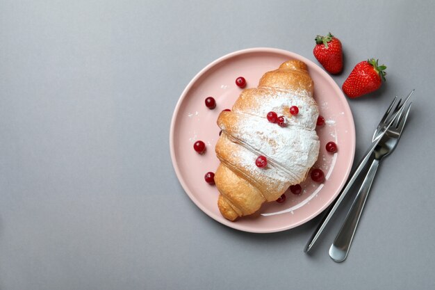 Concetto di gustosa colazione con croissant su grigio