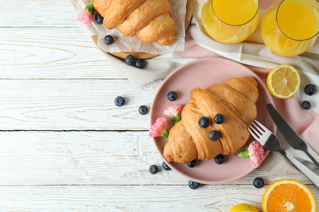 Concetto di gustosa colazione con croissant su legno bianco