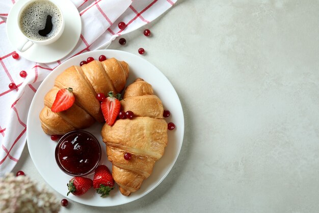 Concetto di gustosa colazione con croissant sulla tabella testurizzata bianca