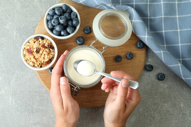 Concetto di gustosa colazione con yogurt su un tavolo grigio strutturato