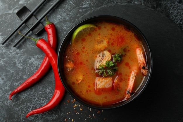 Concetto di gustoso mangiare con la zuppa Tom yum su sfondo nero smokey