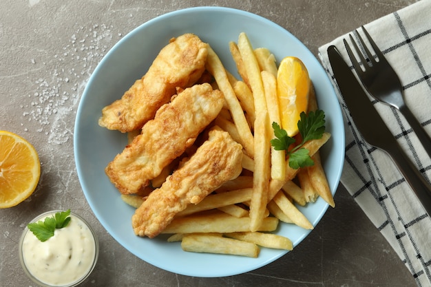 Concetto di gustoso mangiare con pesce fritto e patatine fritte sulla tabella strutturata grigia