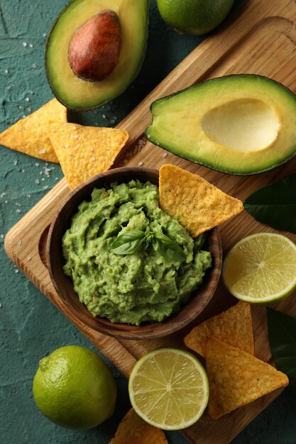 Concetto di gustoso mangiare con una ciotola di guacamole su sfondo verde con texture