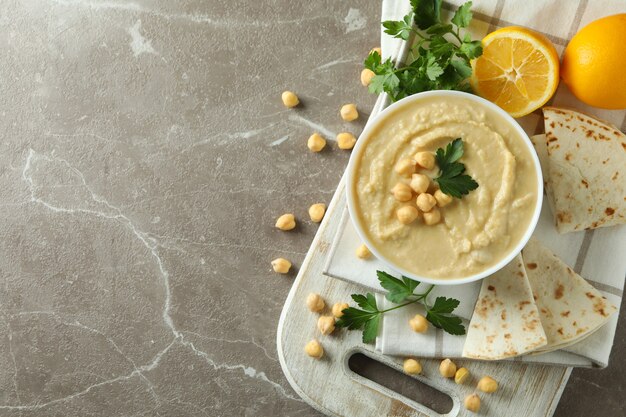 Concetto di gustoso mangiare con una ciotola di hummus sulla superficie grigia