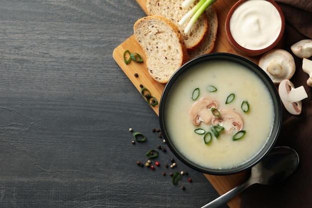 Concetto di gustoso pranzo con ciotola di zuppa di funghi su legno scuro