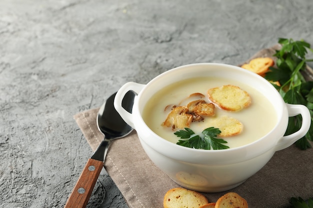 Concetto di gustoso pranzo con scodella di zuppa di funghi su grigio