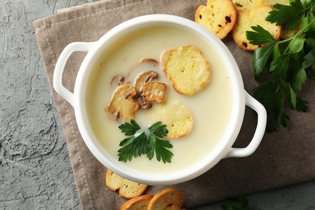 Concetto di gustoso pranzo con scodella di zuppa di funghi su grigio