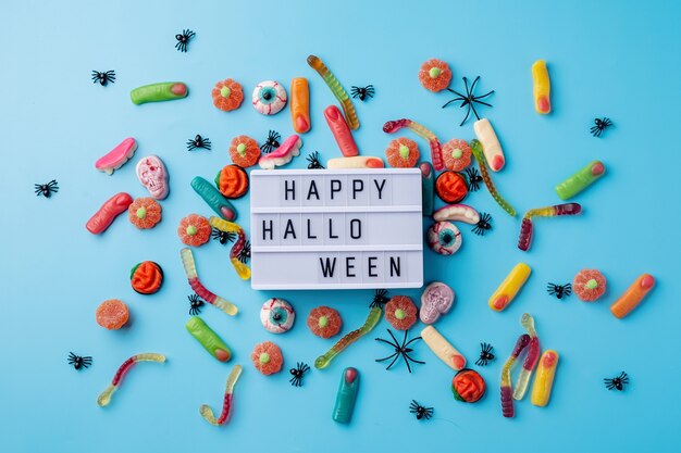 concetto di Halloween. Decorazioni per feste di Halloween con lightbox con parole Happy Halloween, dolci, zucche vista dall'alto piatta su sfondo blu