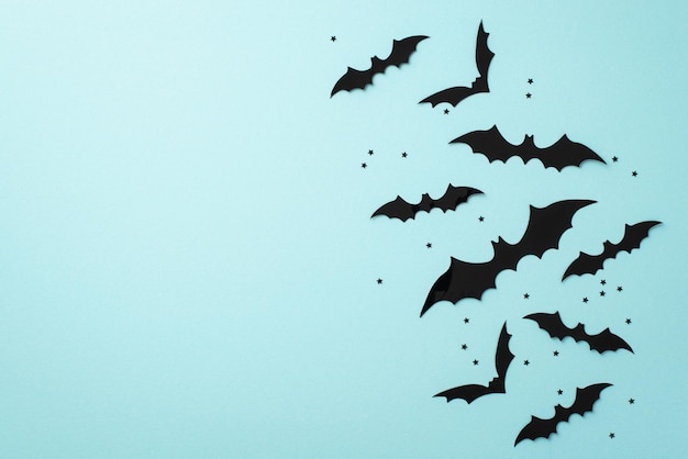 Concetto di Halloween Foto vista dall'alto di sagome di pipistrelli e coriandoli neri su sfondo blu pastello isolato con copyspace