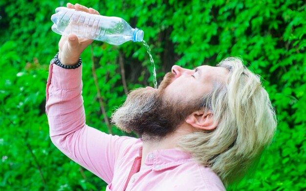 Concetto di idratazione. Acqua potabile dell'uomo barbuto. Maschio con bottiglia d'acqua. Uno stile di vita sano.