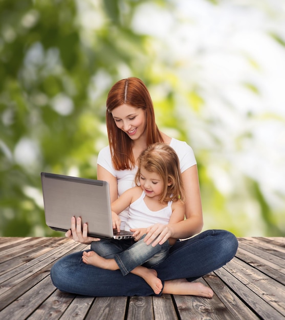 concetto di infanzia, genitorialità e tecnologia - madre felice con adorabile bambina con laptop