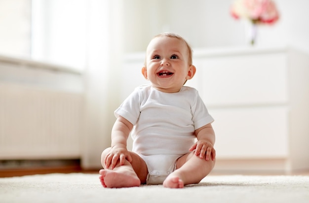 concetto di infanzia, infanzia e persone - bambino felice o bambina seduta sul pavimento a casa