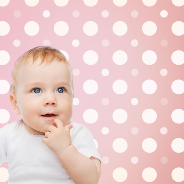 concetto di infanzia, persone e felicità - faccia sorridente della bambina su sfondo rosa e bianco a pois