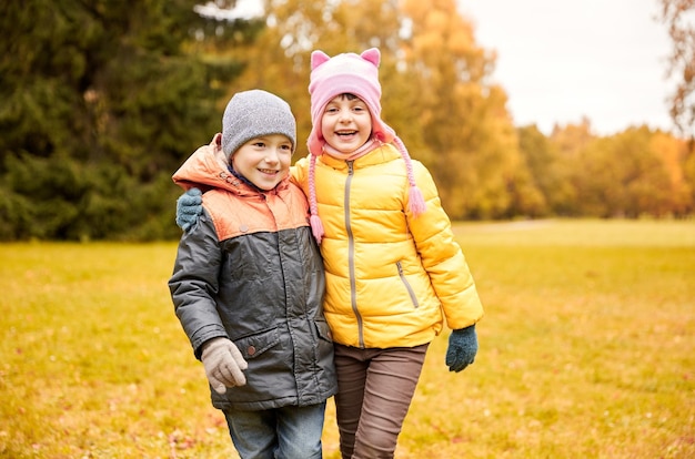 concetto di infanzia, tempo libero, amicizia e persone - bambina felice e ragazzo nel parco autunnale