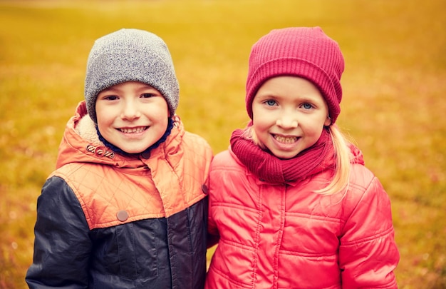 concetto di infanzia, tempo libero, amicizia e persone - bambina felice e ragazzo nel parco autunnale