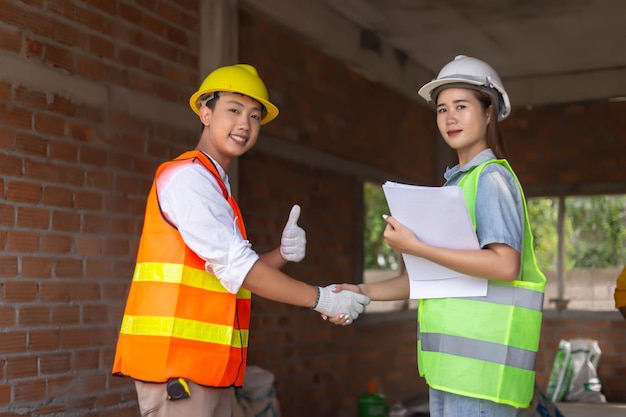 Concetto di ingegnere Il lavoratore di ingegneria maschile che indossa l'uniforme di arance che stringe la mano