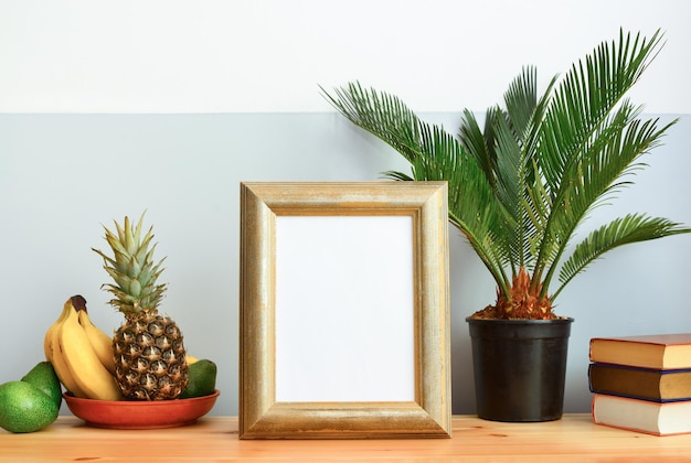 Concetto di interni tropicali estivi, cornice con uno spazio vuoto in piedi su una cassettiera progettata da una scuola antica decorata con palme tropicali in una pentola e frutti tropicali in un piatto