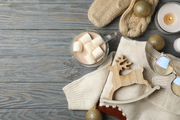 Concetto di inverno con caffè con marshmallow, maglione e candele su fondo in legno