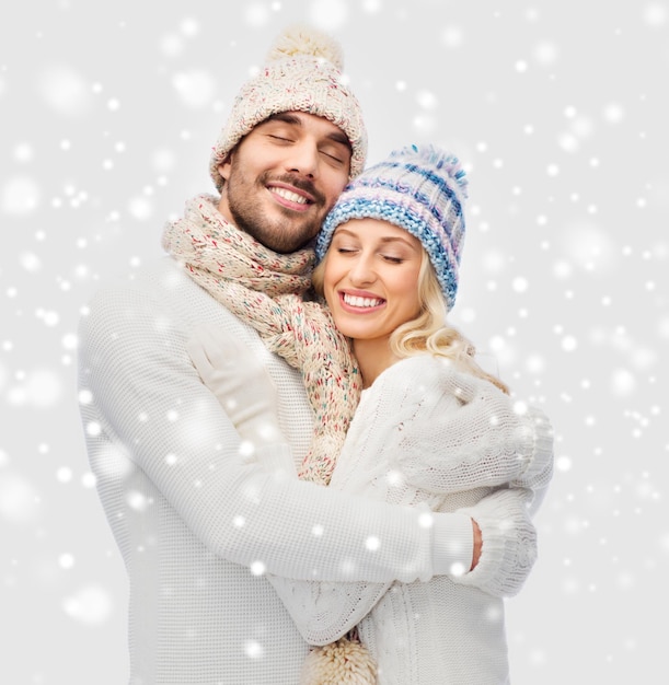 concetto di inverno, moda, coppia, natale e persone - uomo e donna sorridenti in cappelli e avvolgenti sciarpe