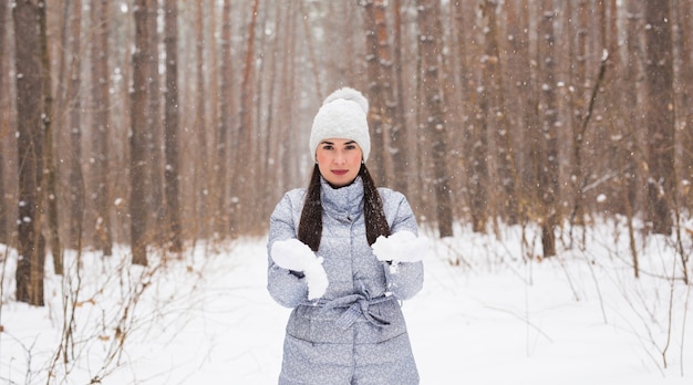 Concetto di inverno, vacanze e persone - la giovane donna allegra è felice di camminare nella foresta invernale con